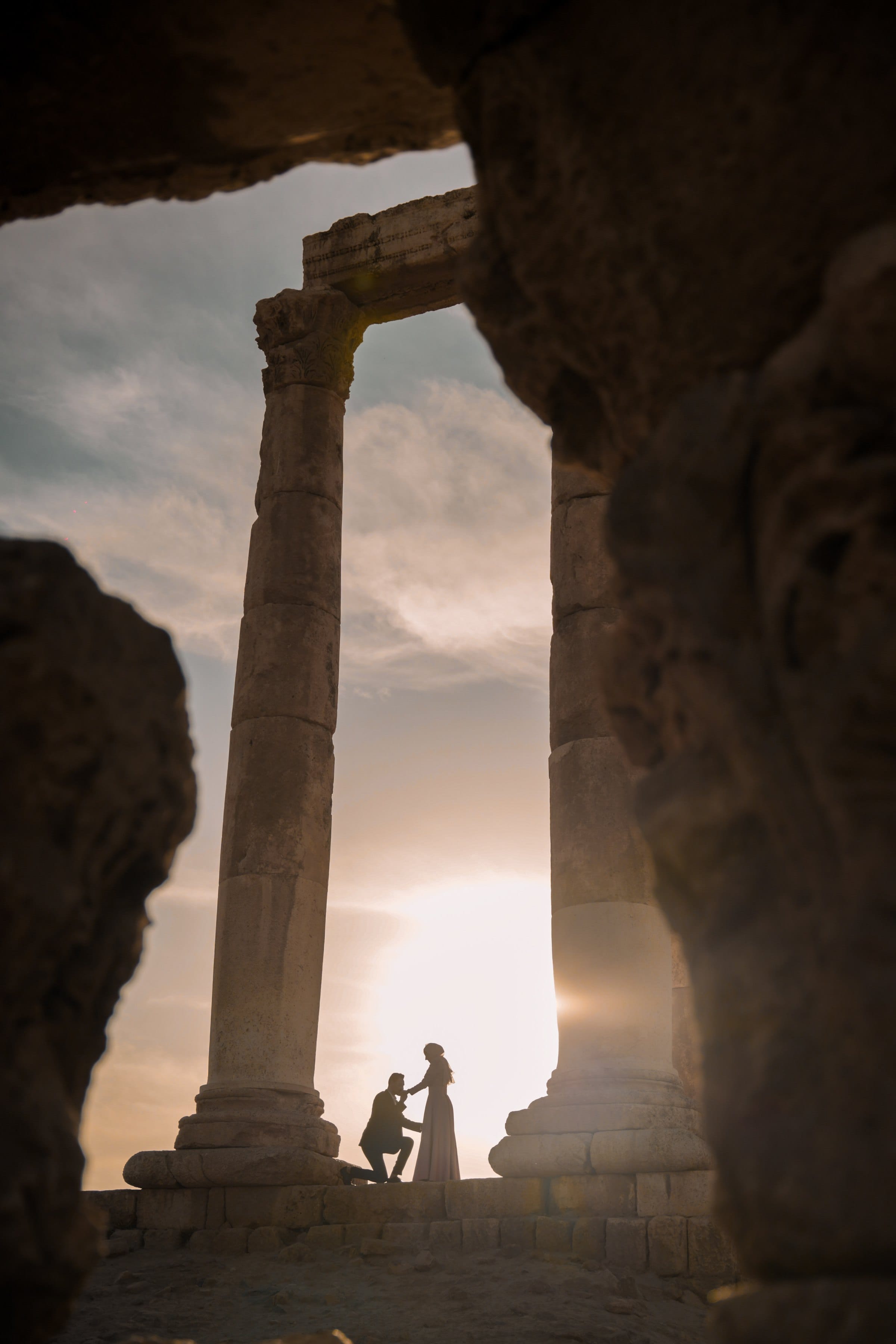 Cinematic silhouette of a bride and groom framed by ancient stone columns at golden hour — female-led Muslim wedding photography by Veil & Light in north Jersey